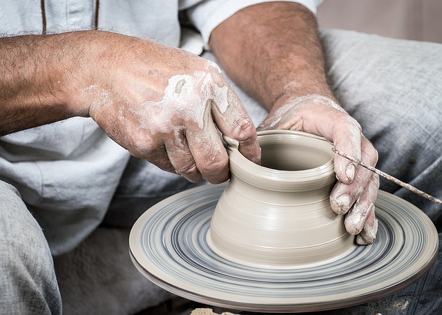 man shaping slay using a potter's wheel