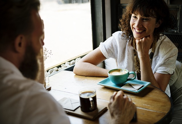 man and woman talking with cups of coffee on table