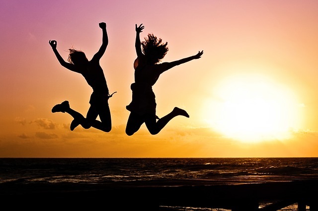 two students jumping in air against sunset