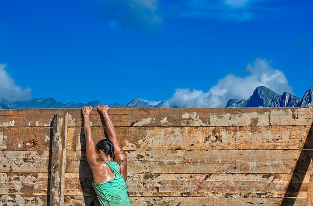 woman runner on an obstacle course at high wall
