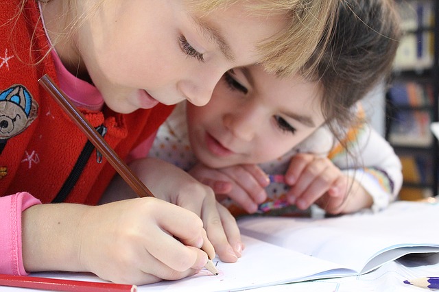 two young girls working together with one writing