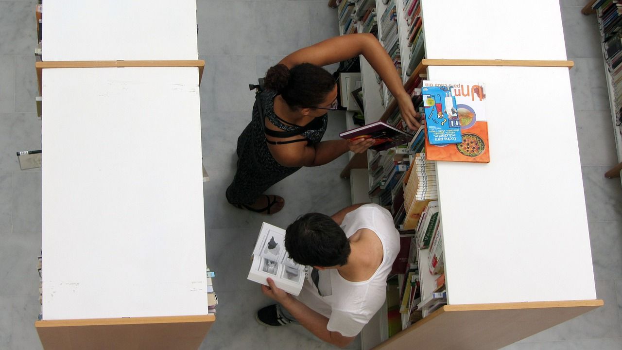 two students near bookshelves in college library