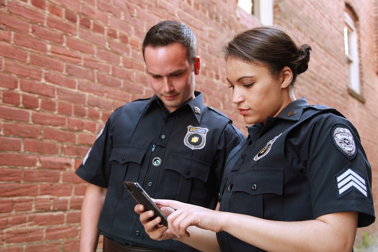 two police officers, one man and one woman looking at cellphone