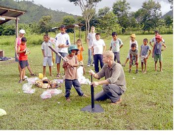 Peace Corps worker helping chilren play t-ball