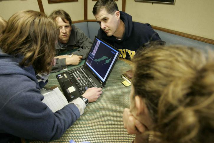 four biostatisticians working around a laptop computers