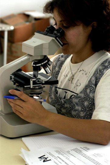 female epidemiologist looking in a microscope