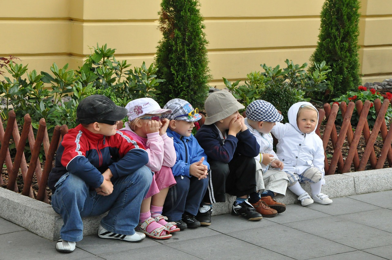 sic children sitting on the curb wearing jackets and hats