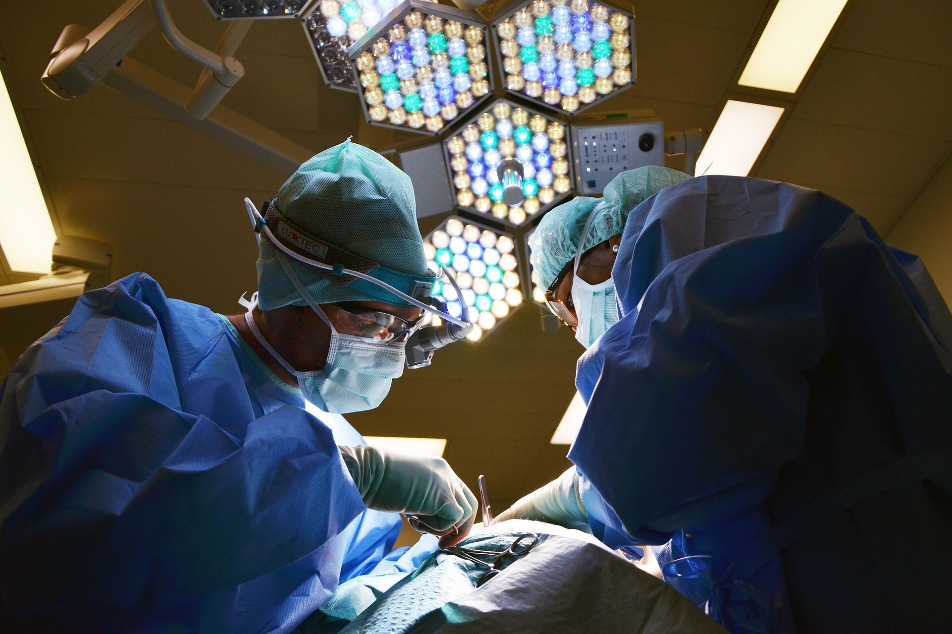two doctors in full operating gear performing surgery on a patient