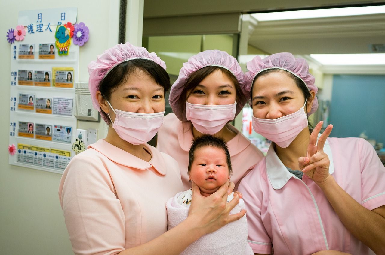 three Asian nurses cholding a brand new baby