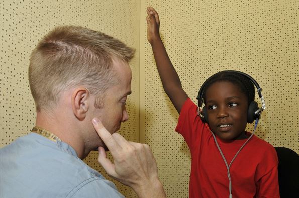 speech pathologist working with African American child with headphones to identify sounds