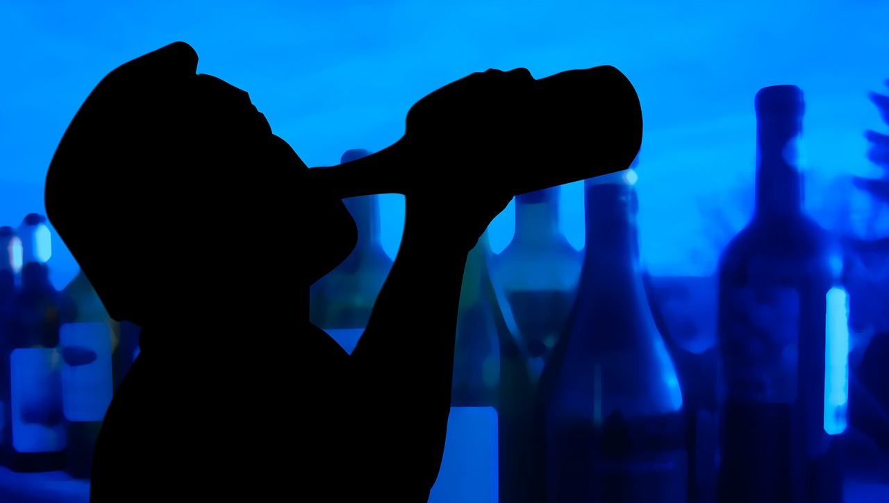 silhoueete of man drinking alcohol and other alcohol bottles