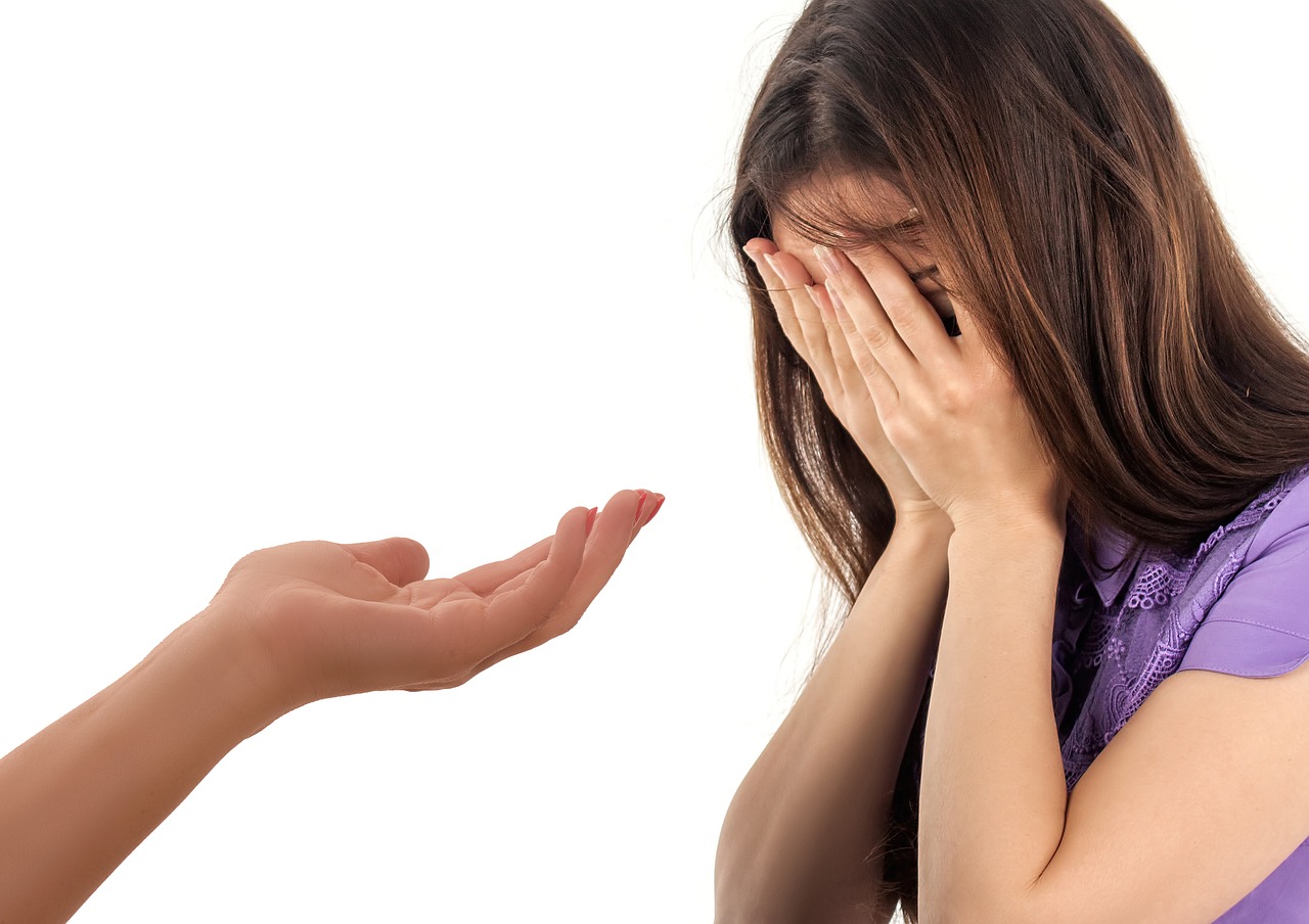 hand being offered to help a woman who has hands over face and seems upset