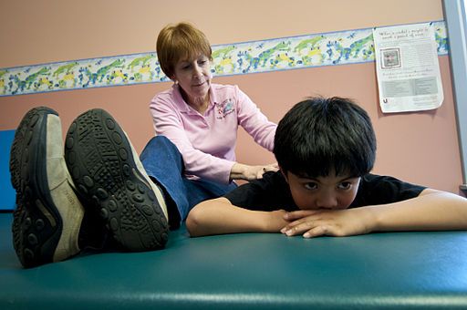 female occupational therapist working with male child who is laying down